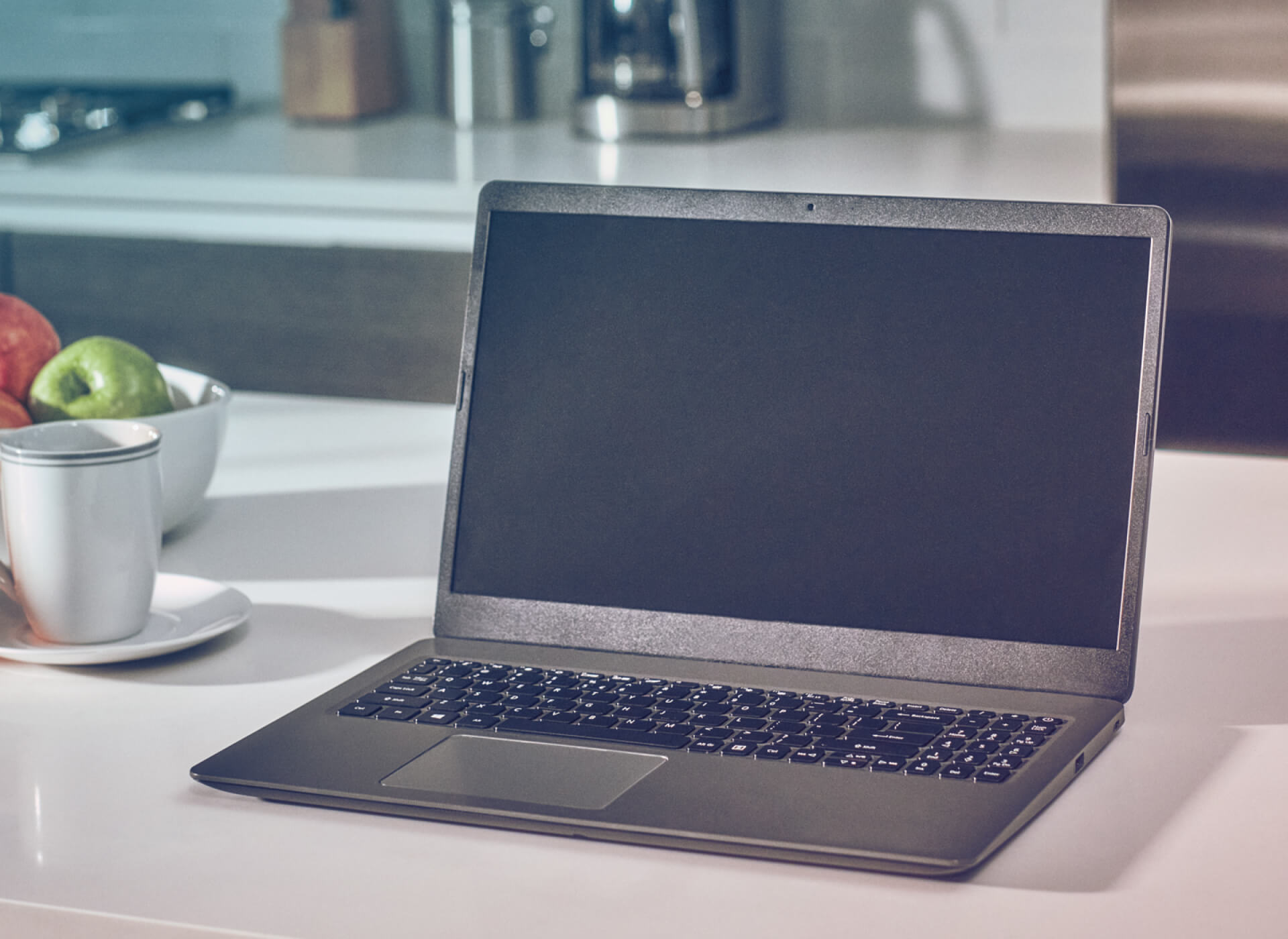 A laptop on a kitchen counter.